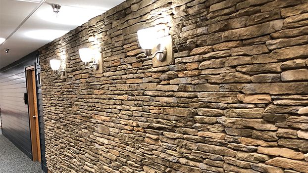 A dimly lit stone wall with elegant sconces enhancing its rustic charm.
