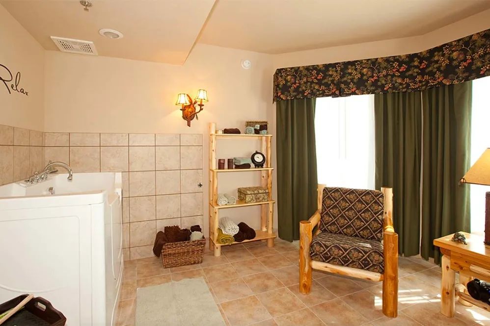 Cozy living room with a patterned chair, shelf, and window with curtains.