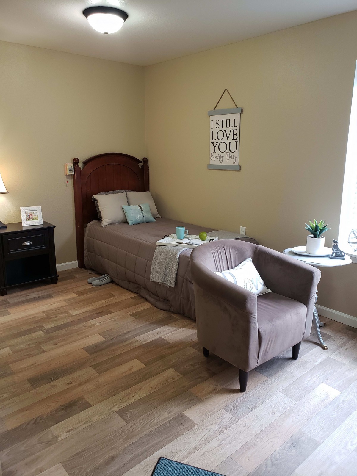 A cozy, well-lit bedroom with a single bed, armchair, and nightstand.