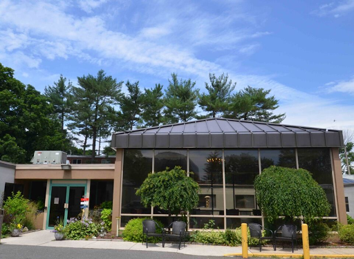 A modern building surrounded by lush greenery under a clear blue sky.