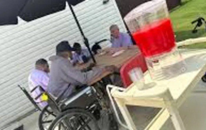 A group of people sitting together at a table outdoors, with drinks in the foreground.