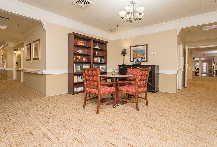 A cozy reading room with a table, chairs, and a bookshelf.