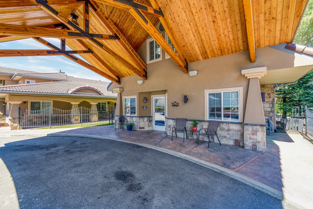 A covered building entrance with patio furniture and a wooden roof structure.