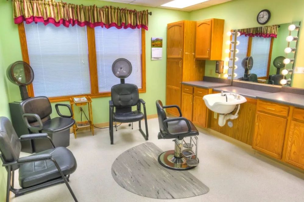 A cozy hair salon interior featuring styling chairs, a dryer, and a sink with a mirror.