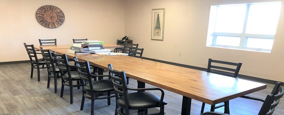 An empty conference room featuring a wooden meeting table and several chairs.
