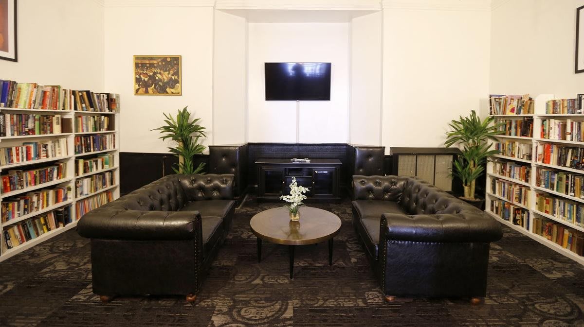 A modern lounge area featuring leather sofas, a central coffee table, a mounted TV, and decorative plants.