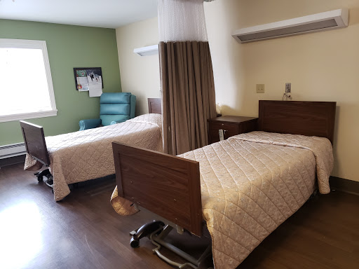 A view of a hospital patient room featuring two beds and a simple, clean layout.