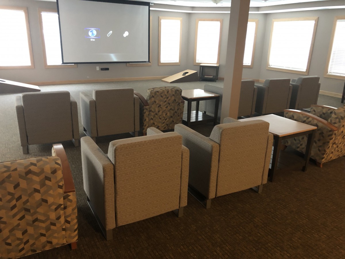 A cozy movie room with comfortable seating arranged in front of a large screen.
