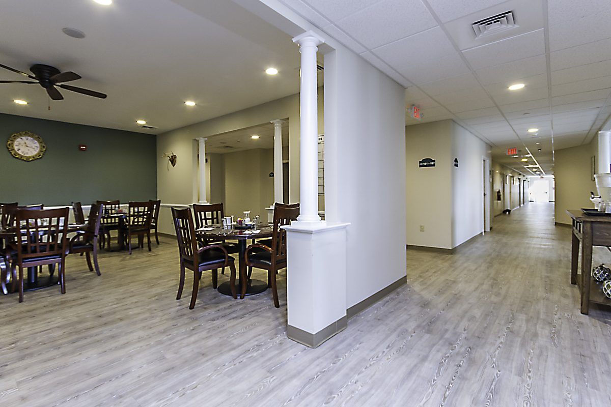 A modern dining area with tables and chairs, featuring wood flooring and column accents.