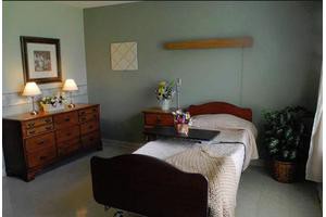 A clean and organized hospital room featuring a single bed with a bedside table and cozy lighting.
