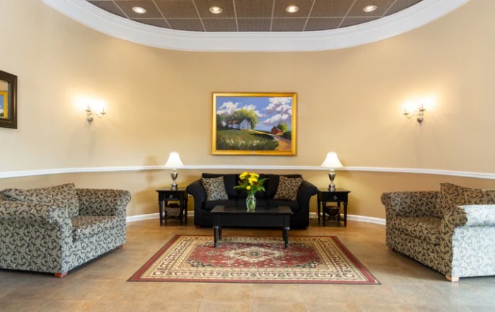 A well-decorated lobby area featuring a sofa, armchairs, coffee table, and wall art.