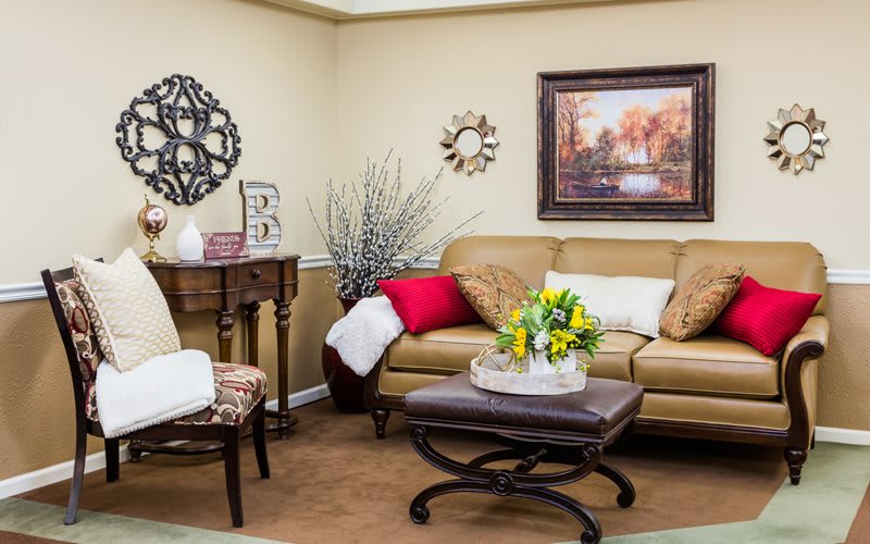 Cozy living room with a leather sofa, decorative cushions, and warm-toned artwork.