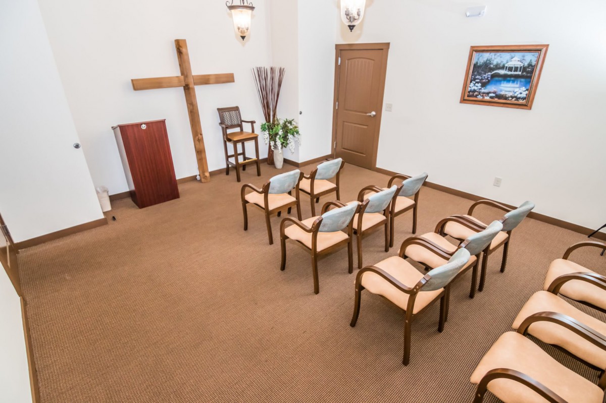 A small chapel with a row of chairs facing a cross and podium.