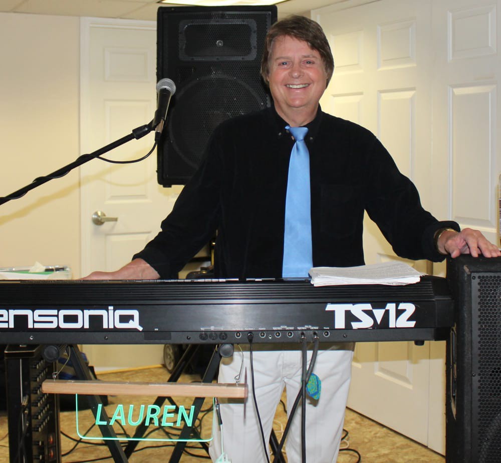 A musician standing behind an Ensoniq TS-12 keyboard, ready to perform indoors.