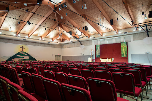 A spacious auditorium with red seating and a wooden ceiling, ready for an event.