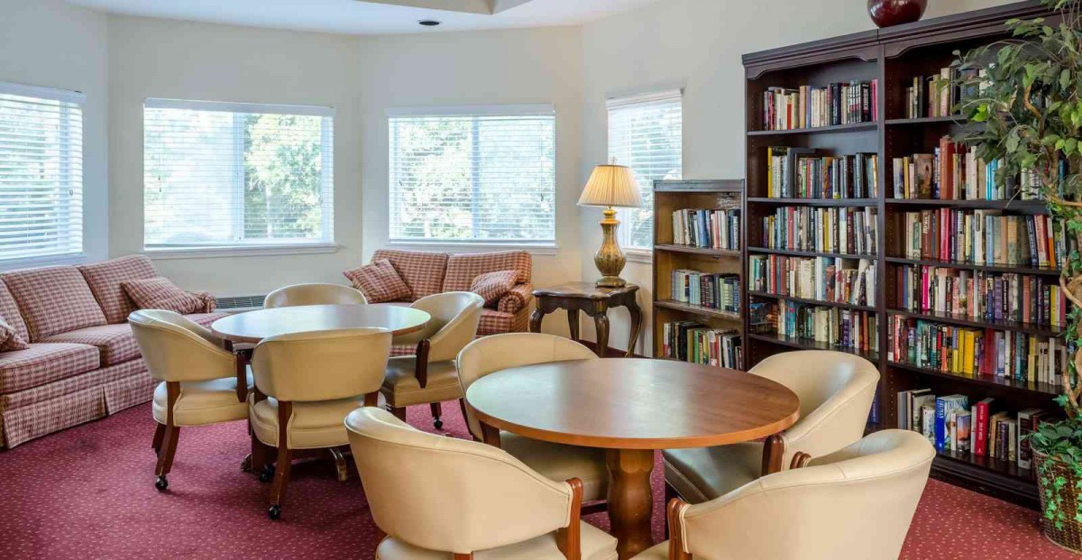 A cozy reading room with bookshelves, tables, and comfortable seating.
