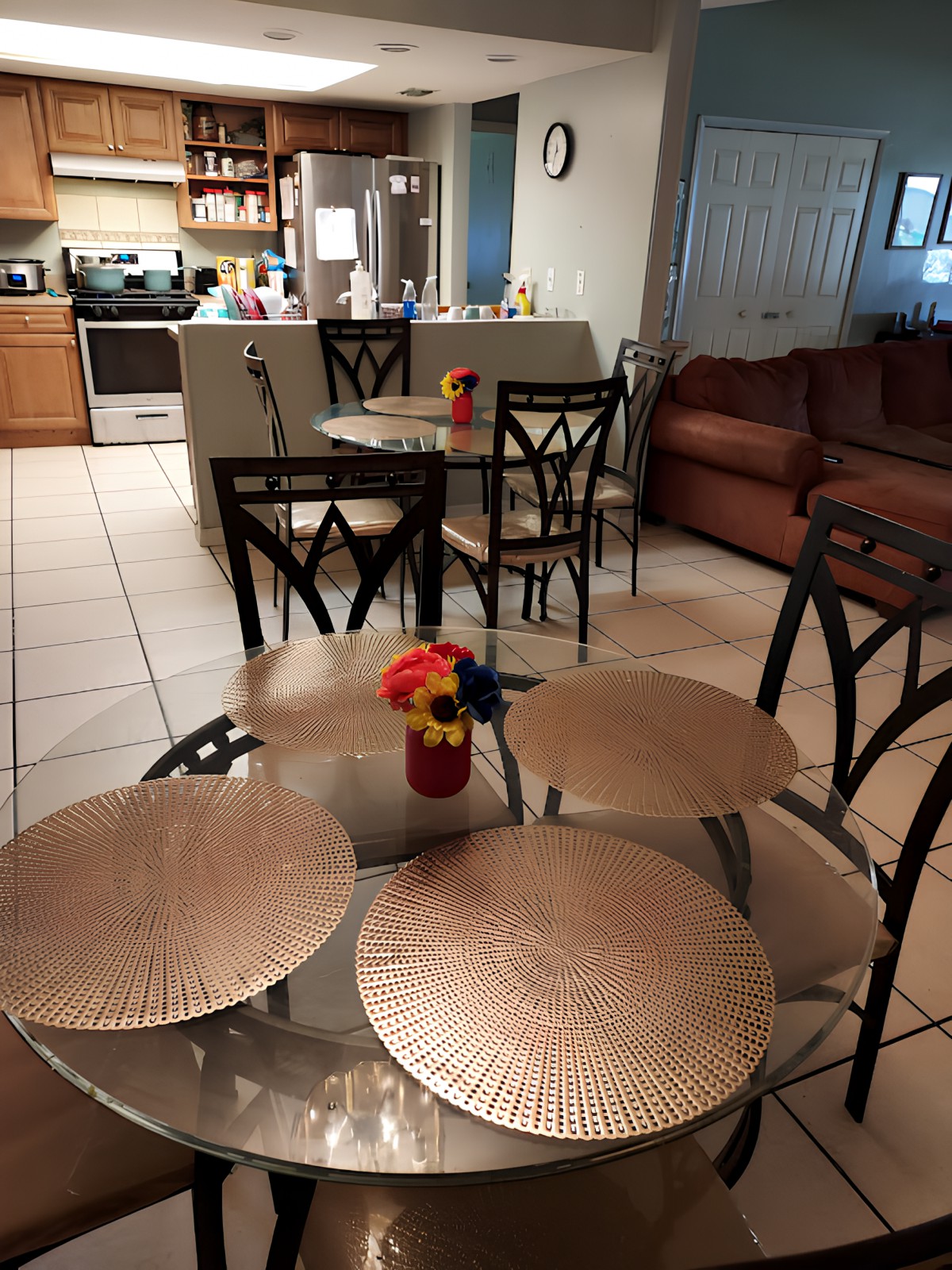 A cozy kitchen and dining area with a table set for dining, featuring placemats and a vase with flowers.