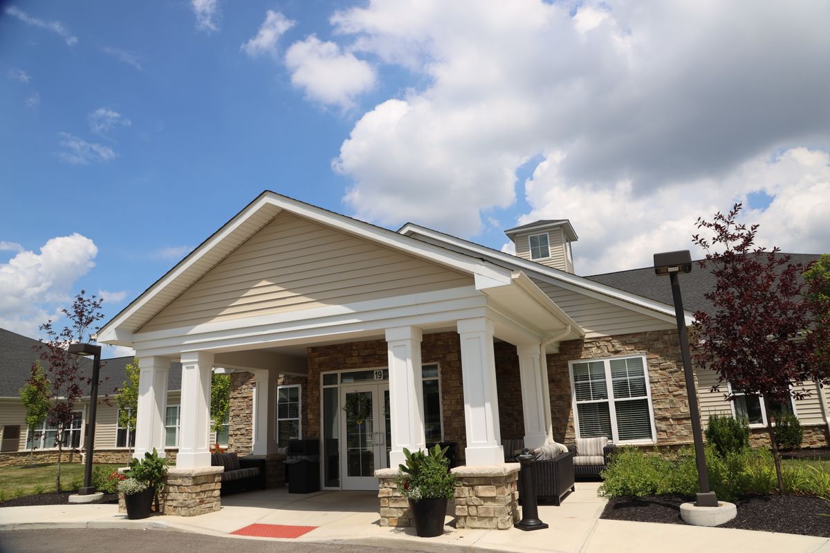 A sunny day at the entrance of a building with columns and a porch.