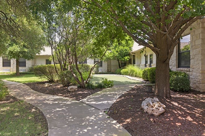 A serene residential house surrounded by lush trees and a well-maintained garden.