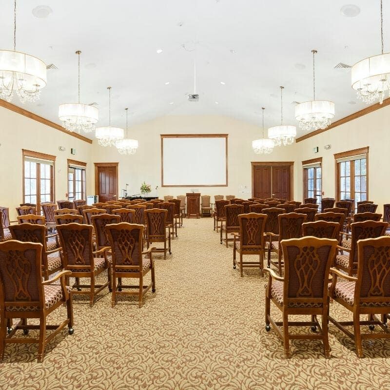 A spacious conference room setup with rows of chairs facing a presentation screen.