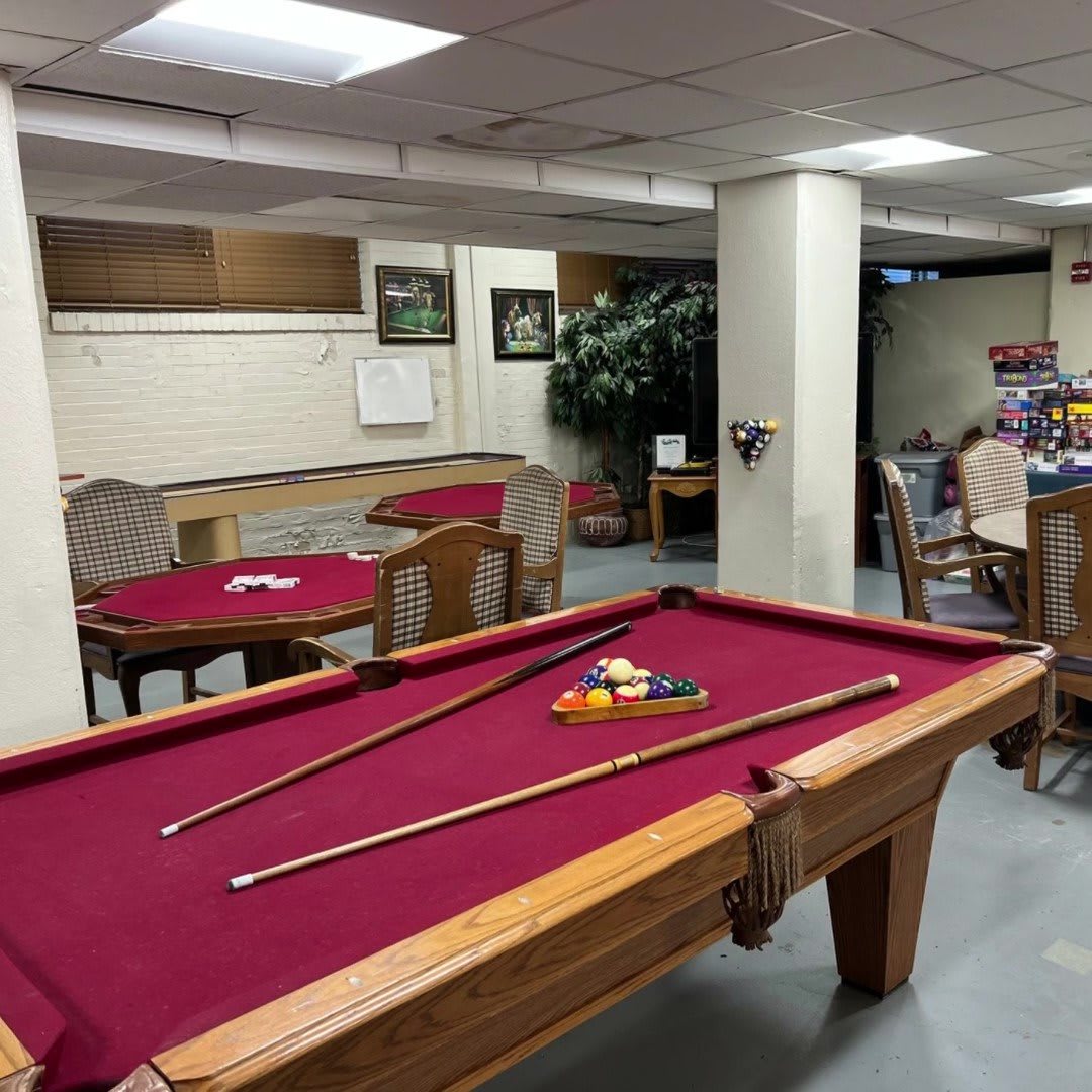 A cozy game room with a red felt pool table and seating area.