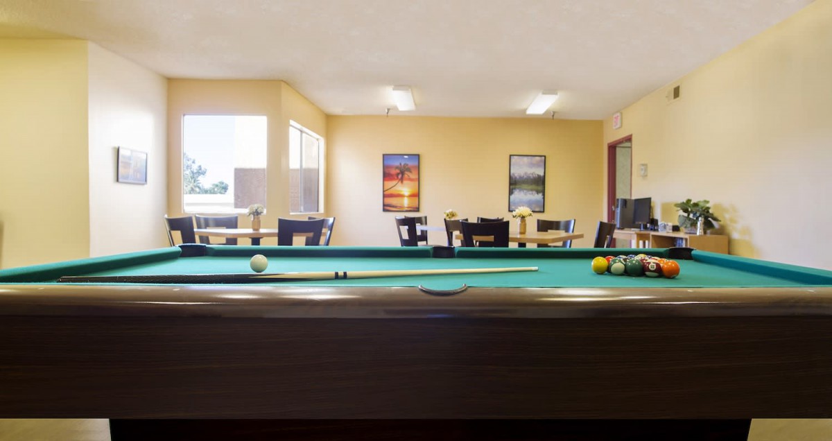 A well-lit game room with a pool table and seating area.