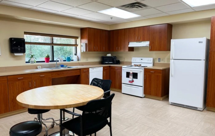 A spacious kitchen with wooden cabinets, a dining table, and modern appliances.