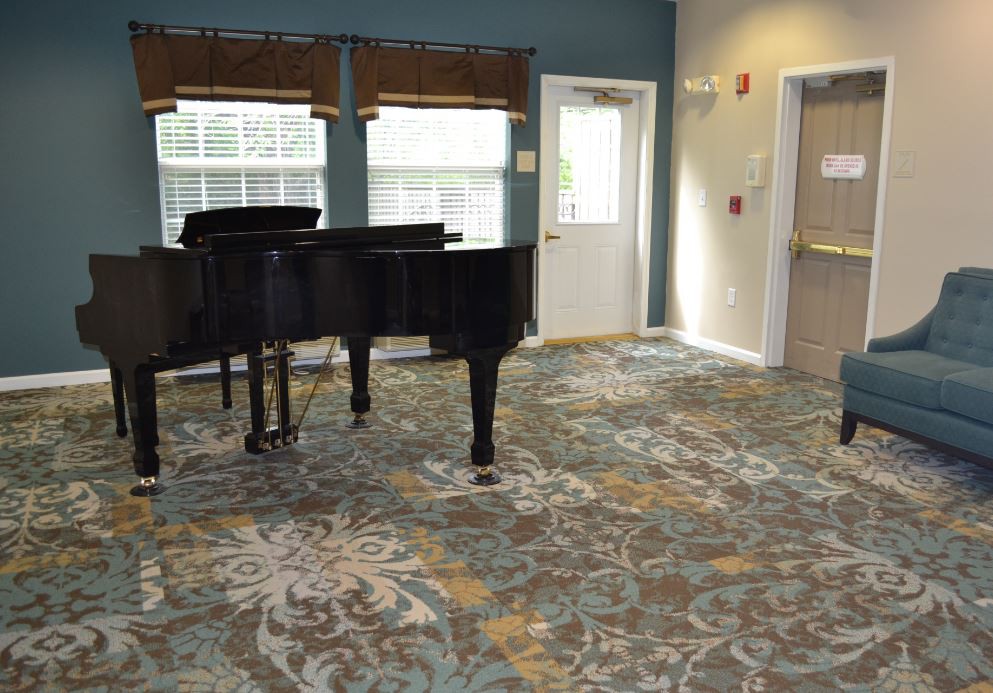 A music room featuring a grand piano and decorative carpet.