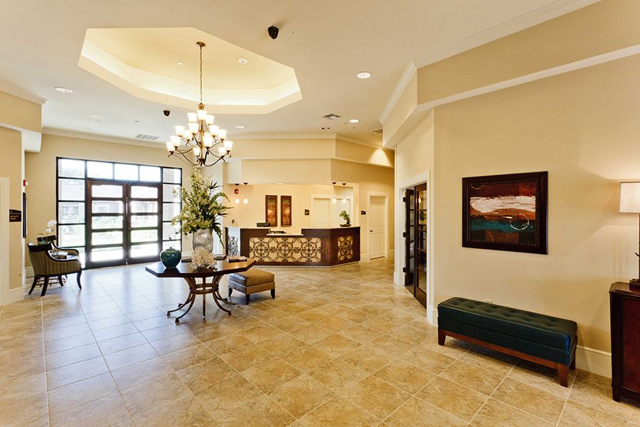 A modern and spacious lobby with a reception desk, chandelier, and comfortable seating.
