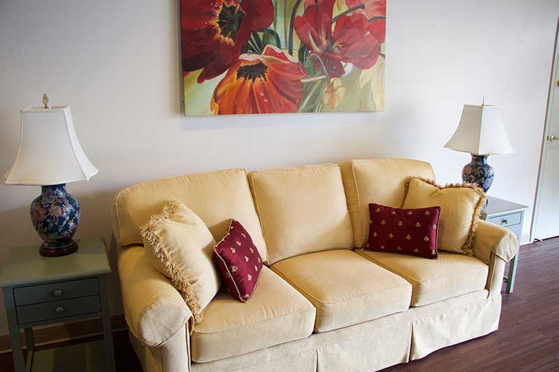 A cozy living room setup with a beige sofa and vibrant red floral artwork.