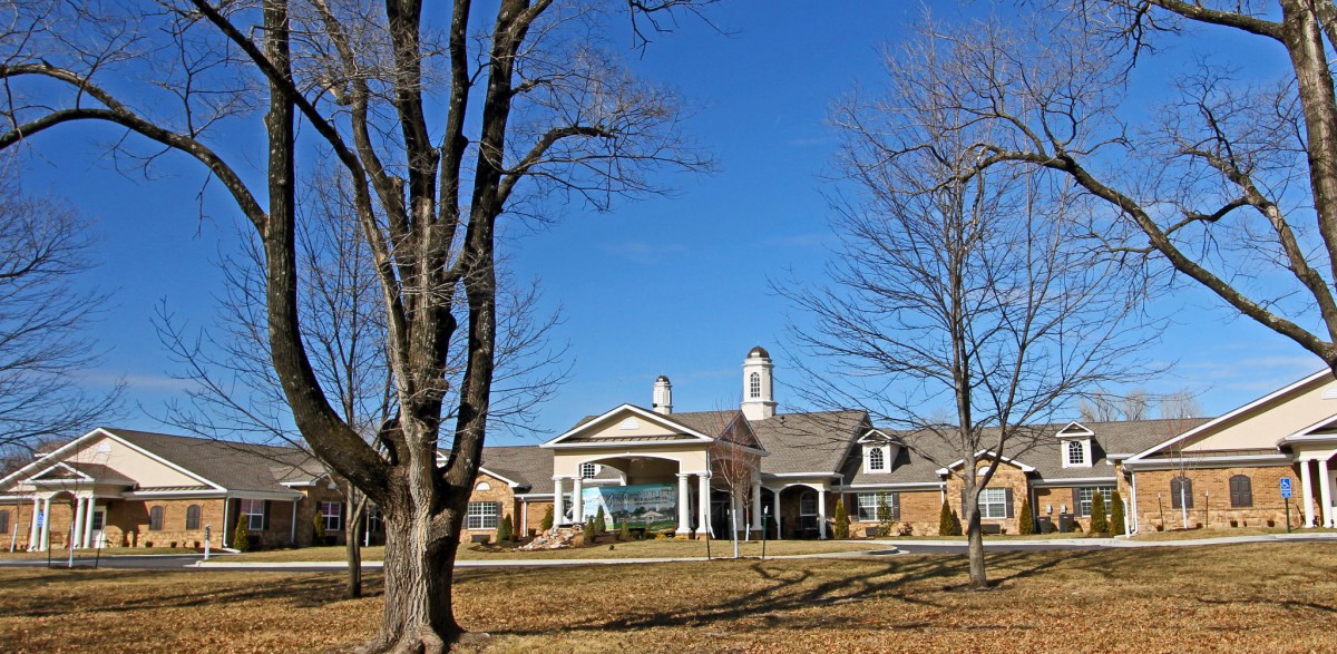 A large, elegant building surrounded by trees and a clear blue sky.
