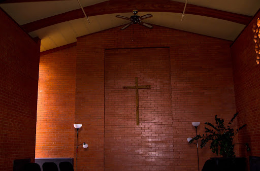 Interior view of a church featuring a wooden cross on a brick wall.