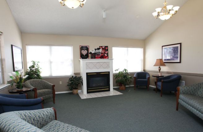 A cozy living room with a fireplace, seating area, and large windows.