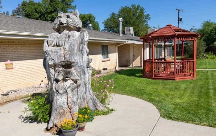 A yard featuring a tree sculpture and a wooden gazebo.