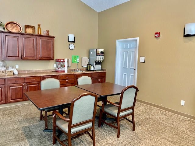 A small conference room with a table, chairs, and a coffee station against beige walls.