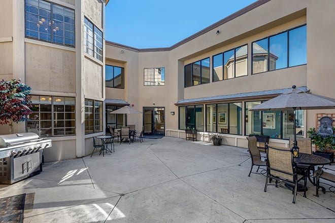 An open courtyard with outdoor seating surrounded by a building with large windows.