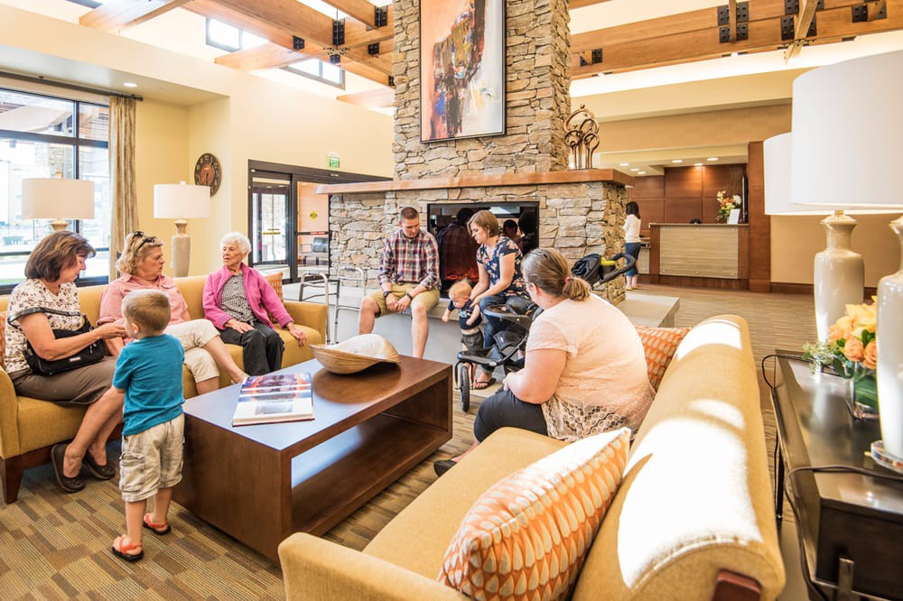 A group of people socializing in a cozy hotel lobby with comfortable seating and a central fireplace.