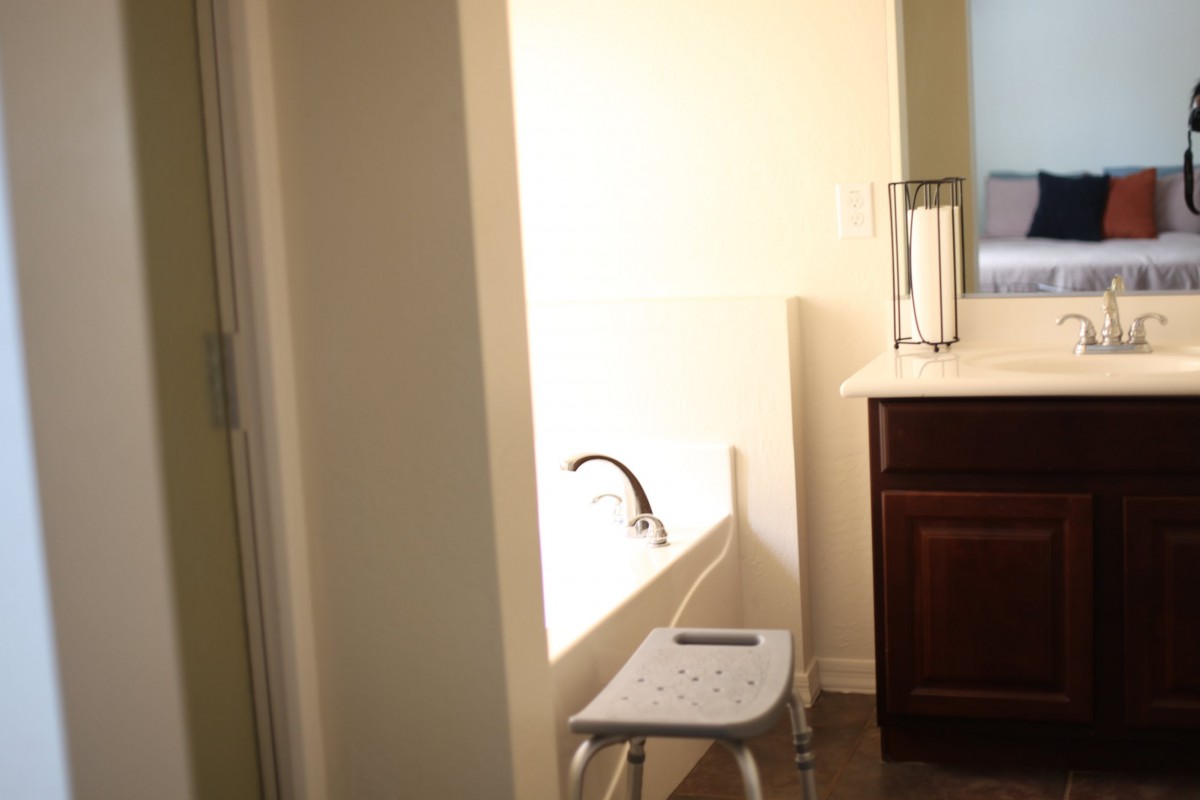 A bathroom with a bathtub, stool, and sink.