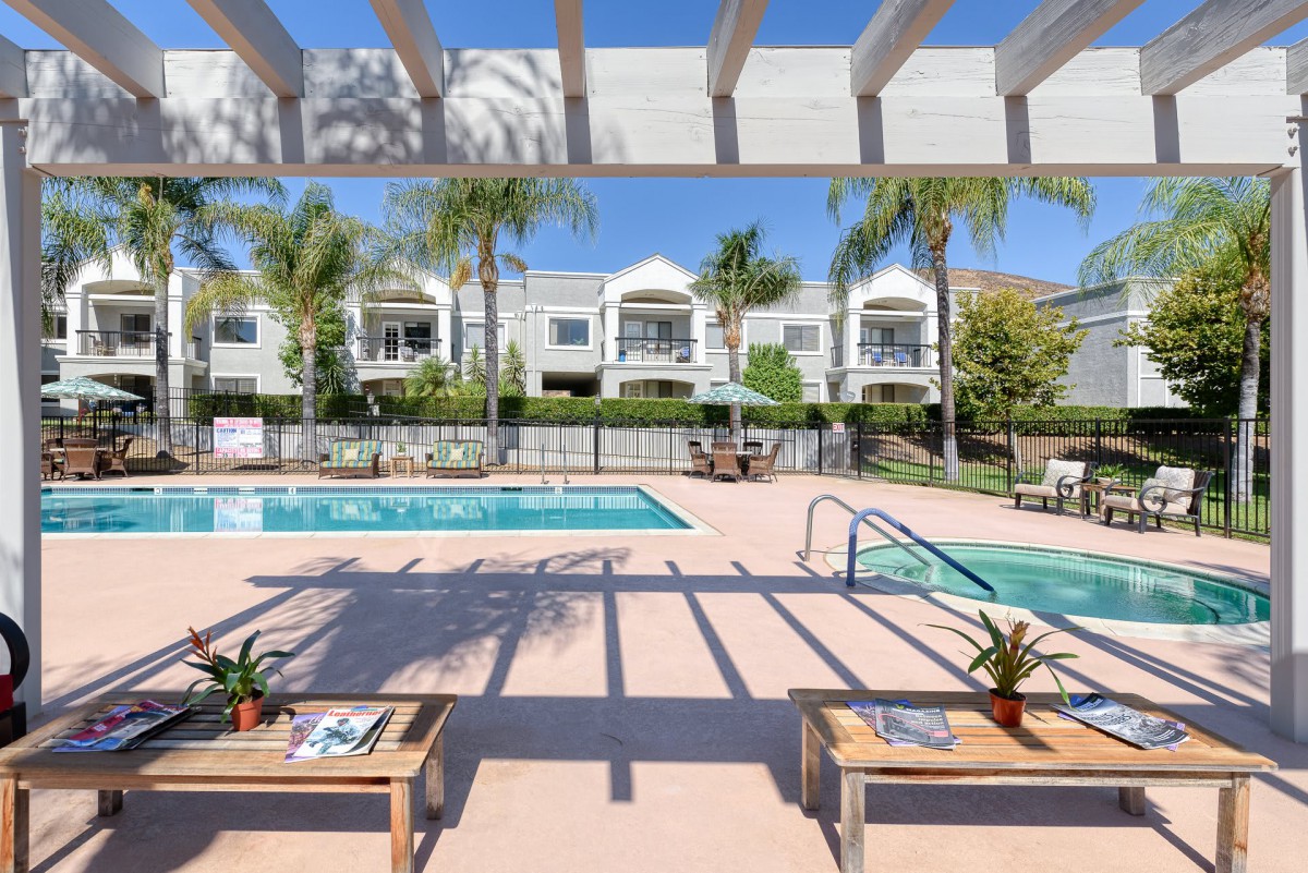 A sunny day at a residential outdoor swimming pool area surrounded by palm trees.