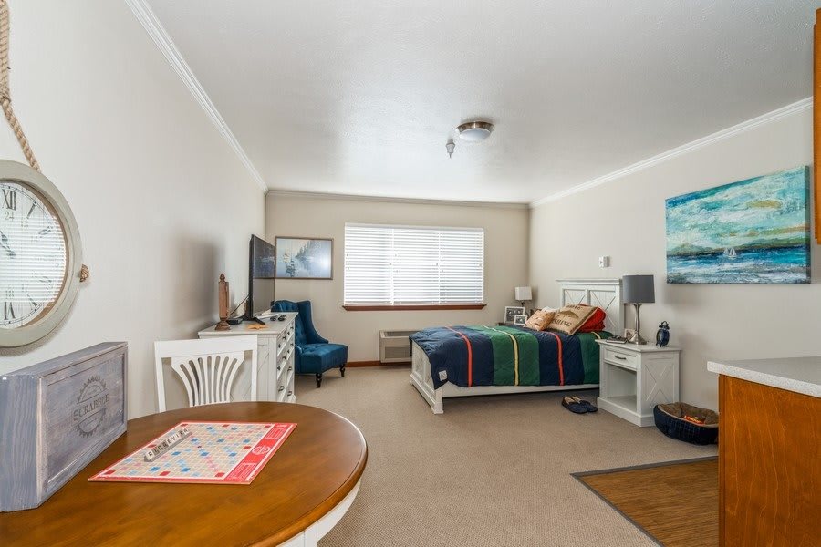 A cozy bedroom with a colorful bedspread, a window allowing natural light, and elegant furnishings.
