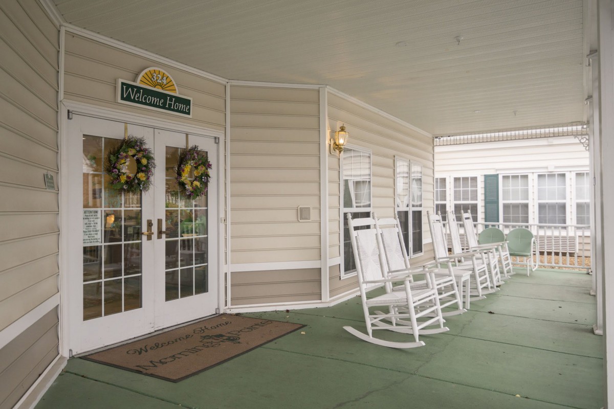 A welcoming porch with white rocking chairs and decorative wreaths near the entrance.