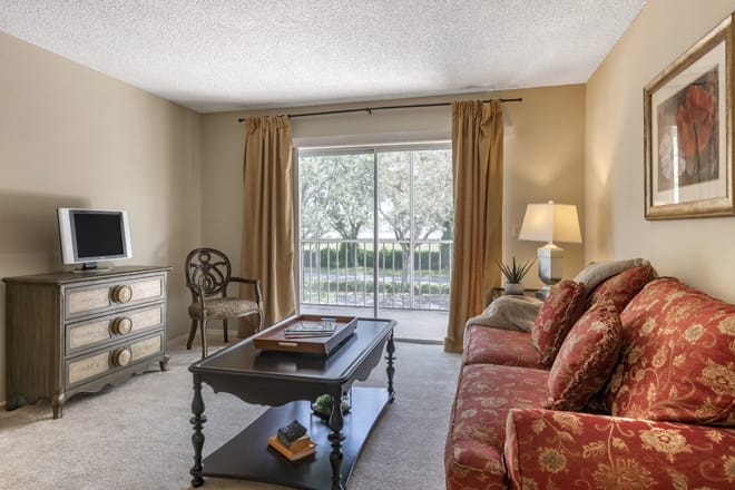 A cozy living room with a sofa, coffee table, and large window with curtains.