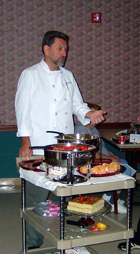 A chef presenting dishes at a buffet setup.