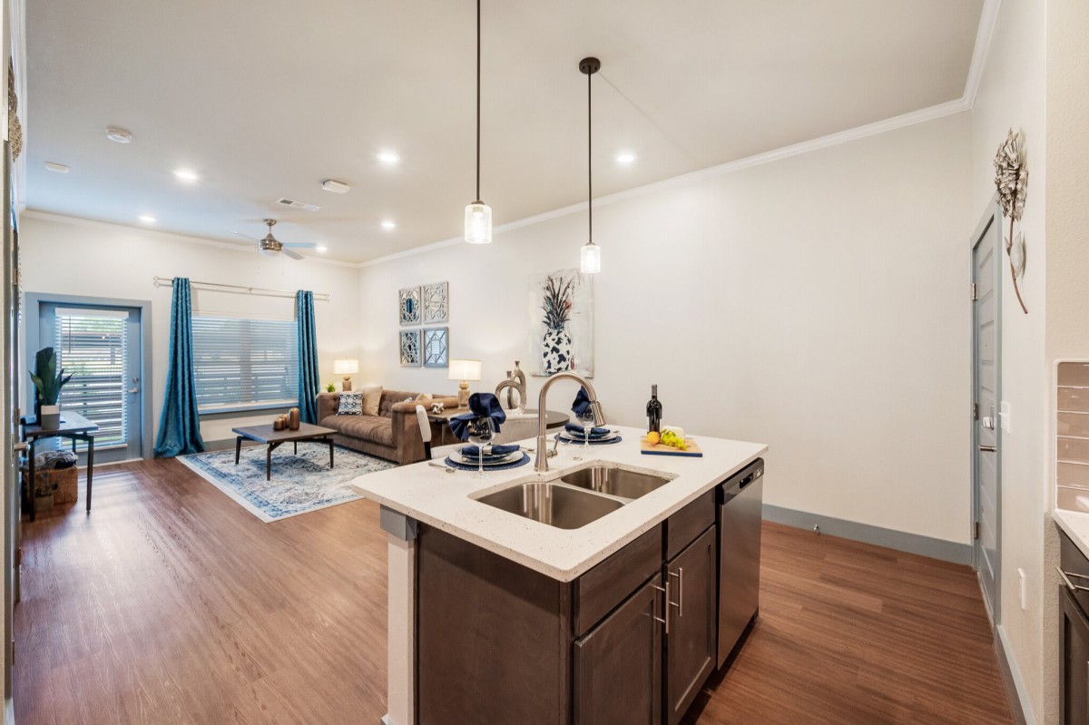 Modern open-concept kitchen and living area with stylish pendant lighting and hardwood flooring.