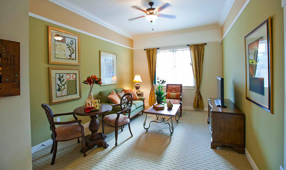 A cozy living room with elegant decor and furniture, featuring a sofa, chairs, coffee table, and wall art.