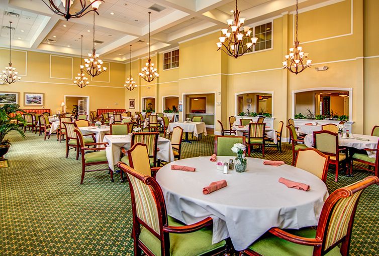 An elegant dining room with neatly arranged tables and chairs, adorned with chandeliers.