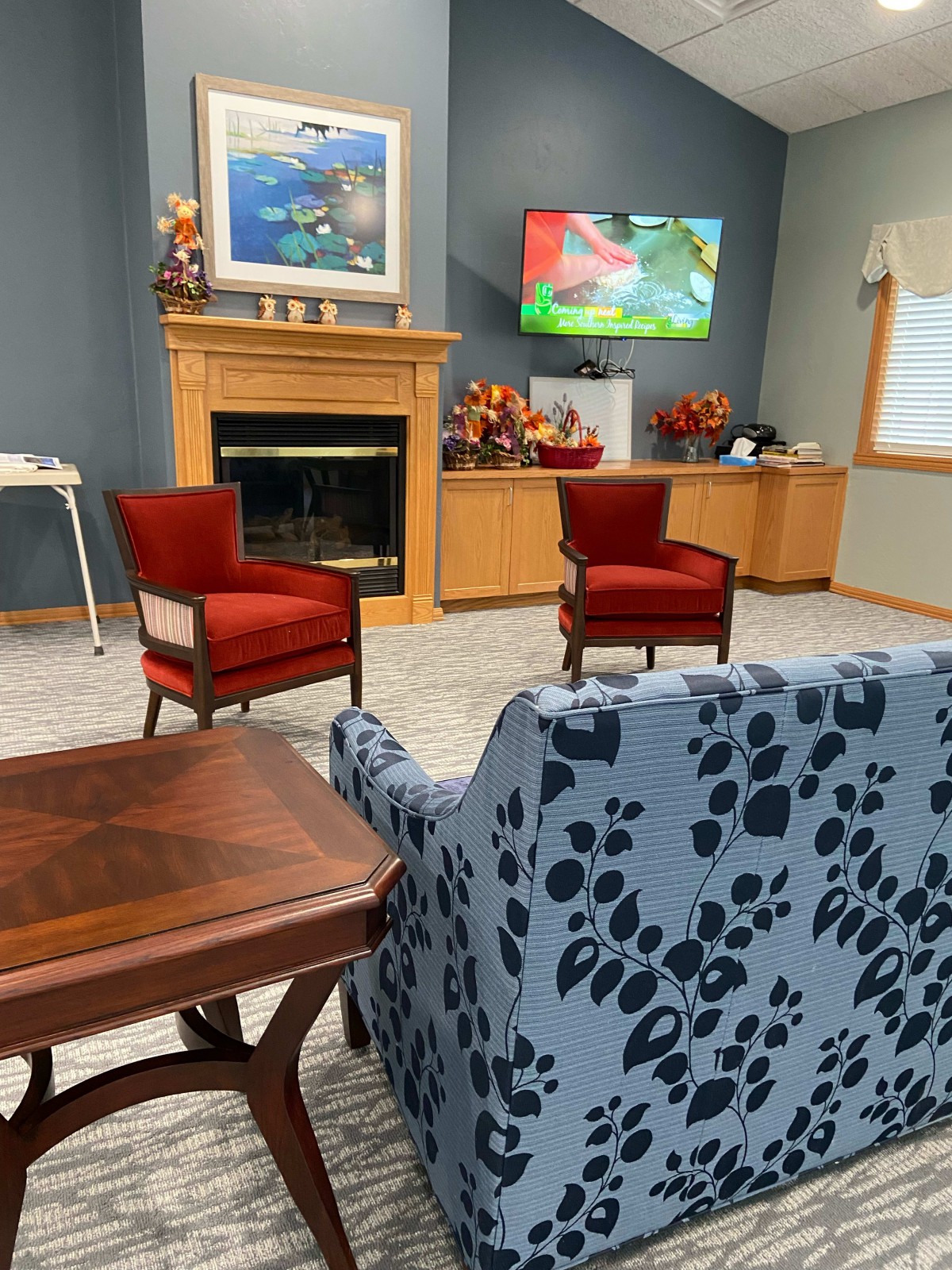 A cozy living room with a fireplace, adorned with red chairs and stylish furniture.