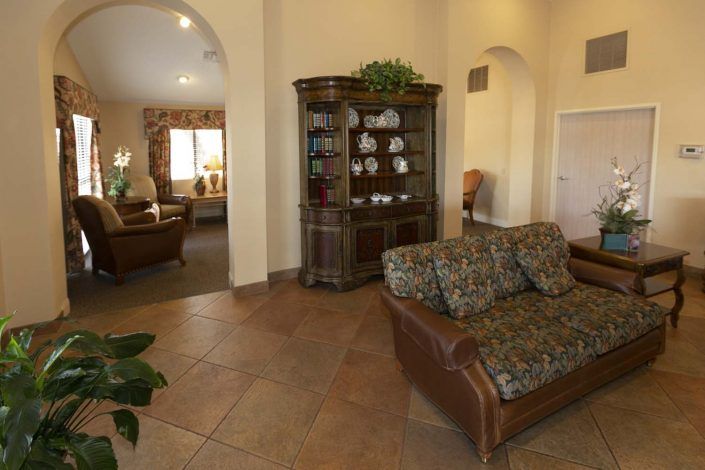 A cozy living room with a tiled floor, featuring a sofa and a wooden cabinet adorned with decorative items.