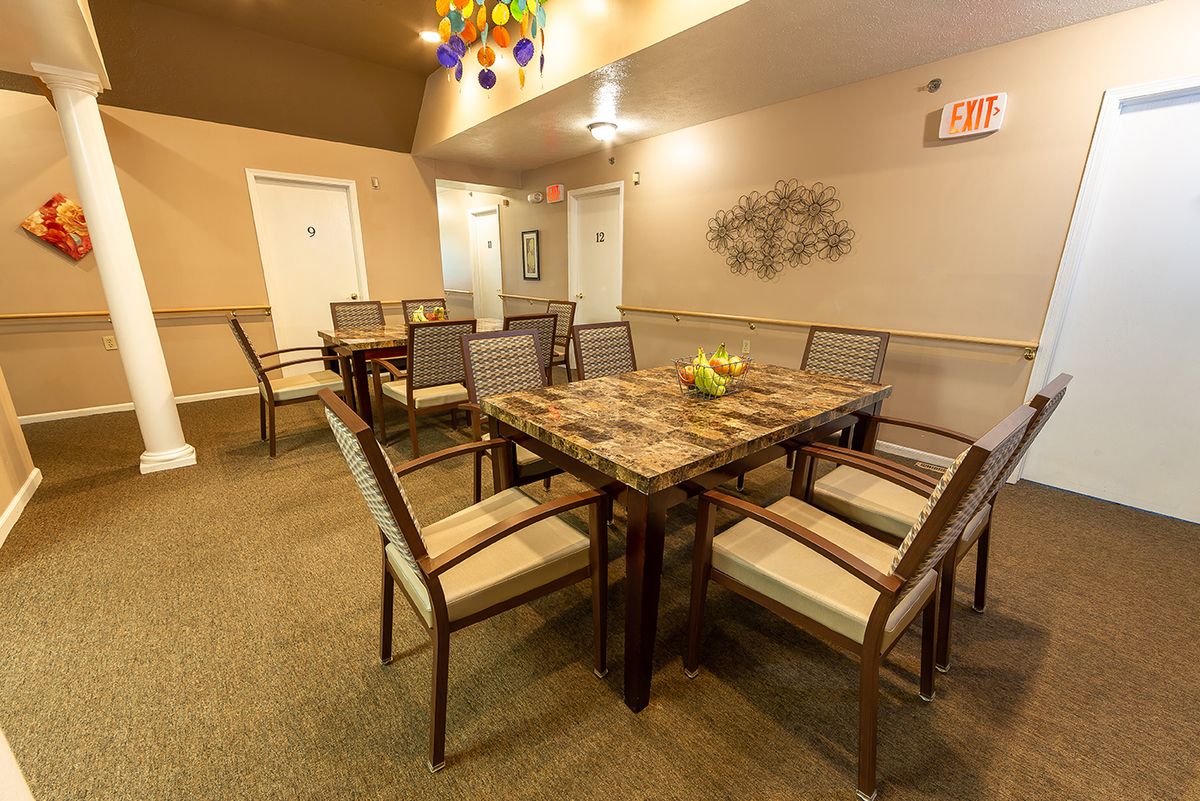 A well-furnished dining area with a large table and several chairs, featuring warm lighting and tasteful decor.