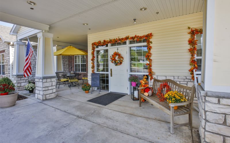 A building entrance decorated with fall-themed items, including a wreath, pumpkins, and garlands.